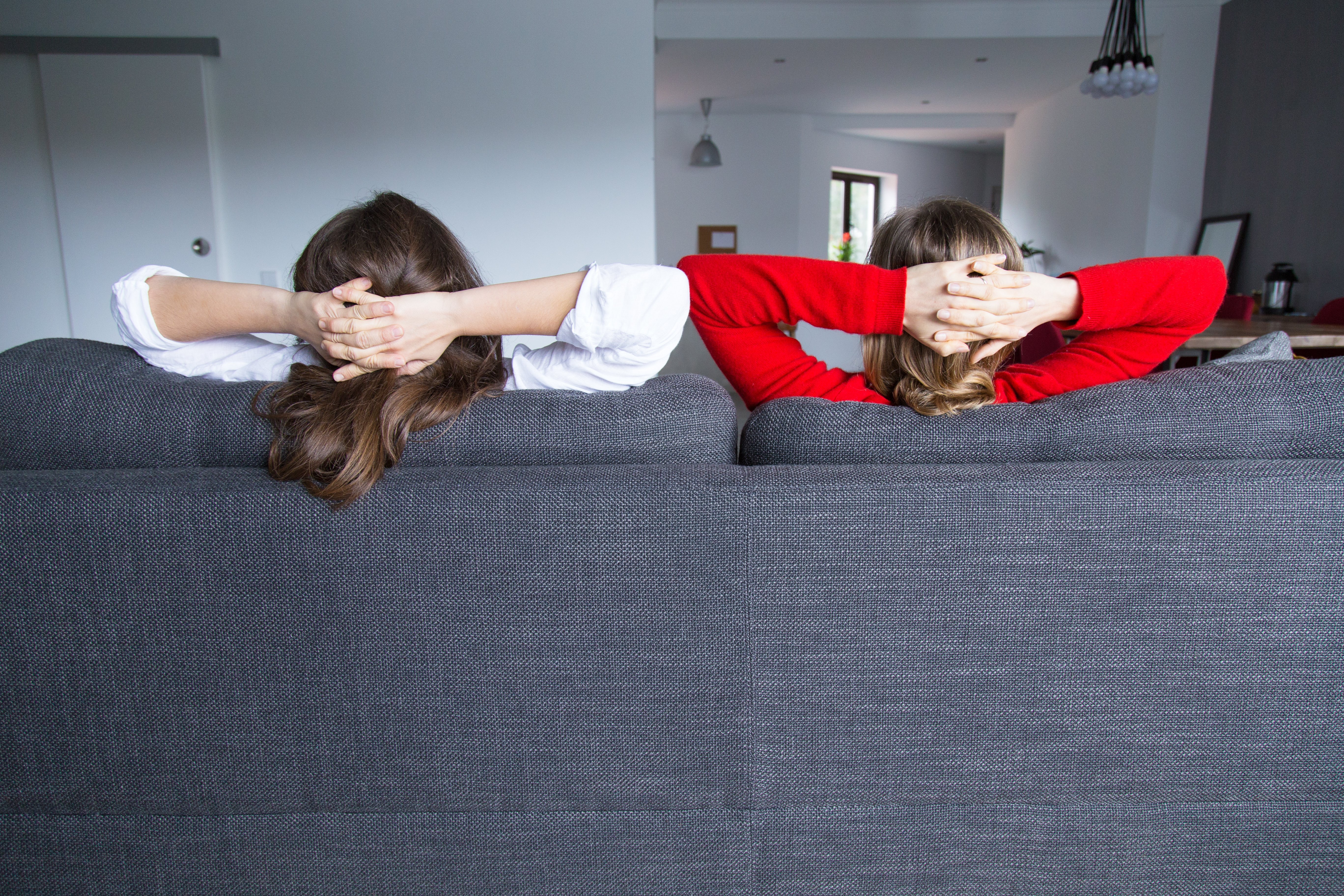 rear-view-female-roommates-relaxing-couch